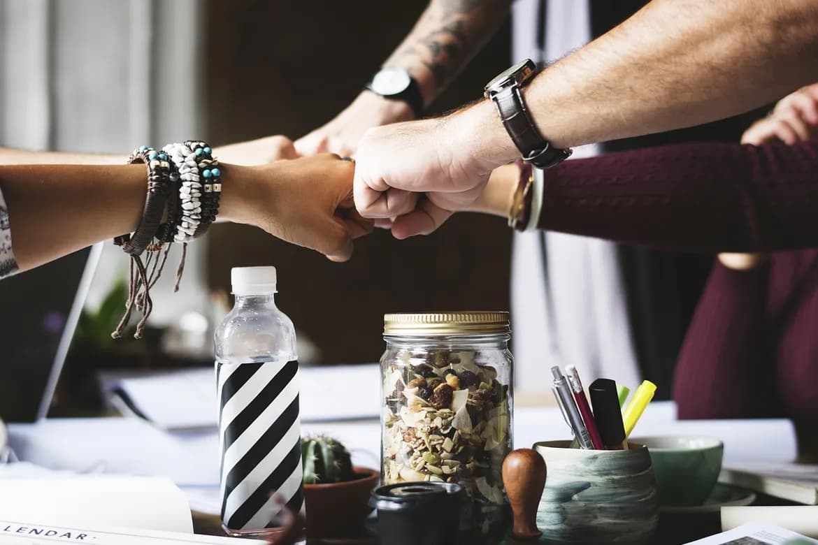 Colegas se cumprimentando com um toque de punhos sobre uma mesa de trabalho