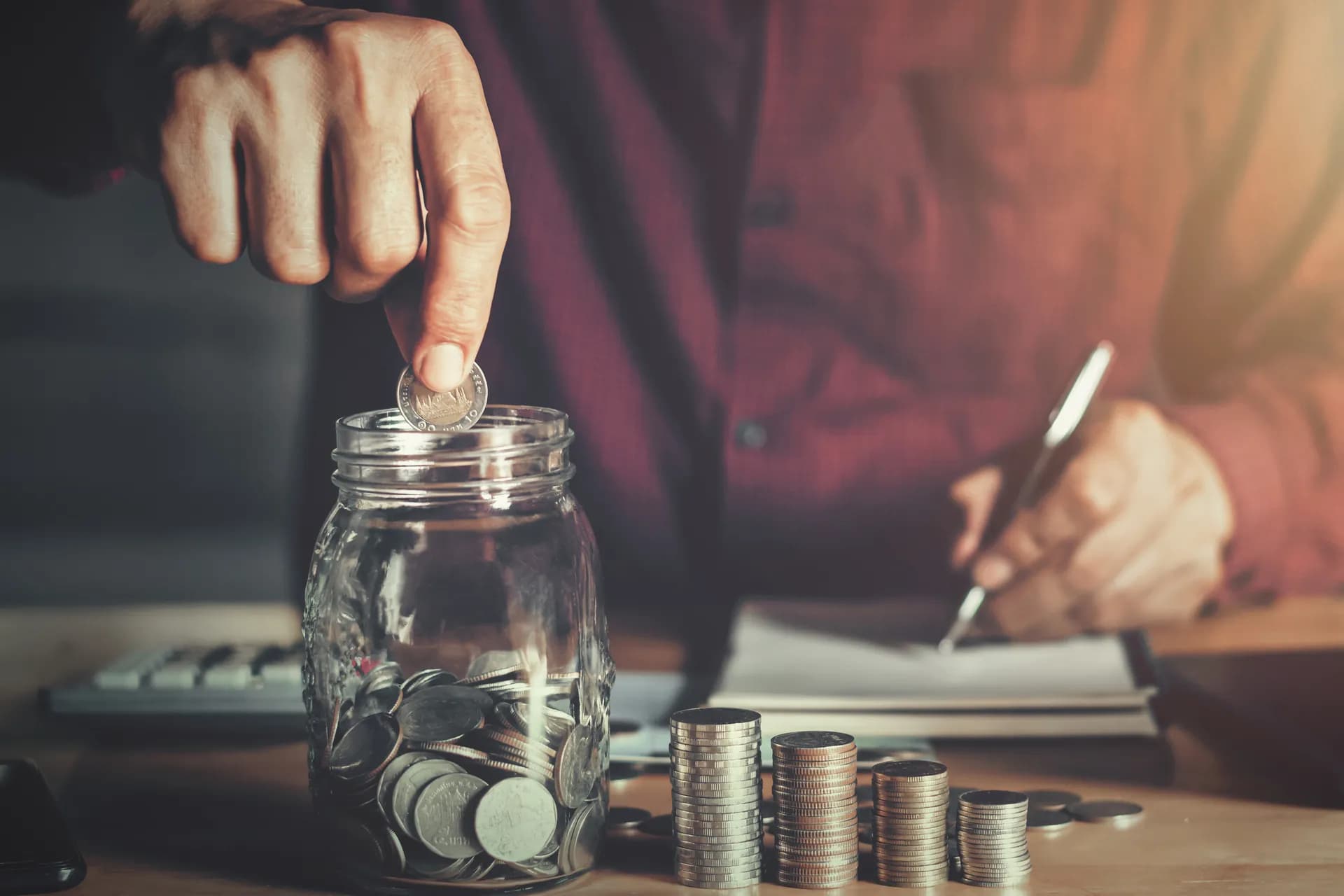 Empresário depositando moedas em copo de vidro